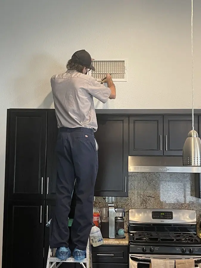 Technician inspecting an air vent during HVAC service in Reno